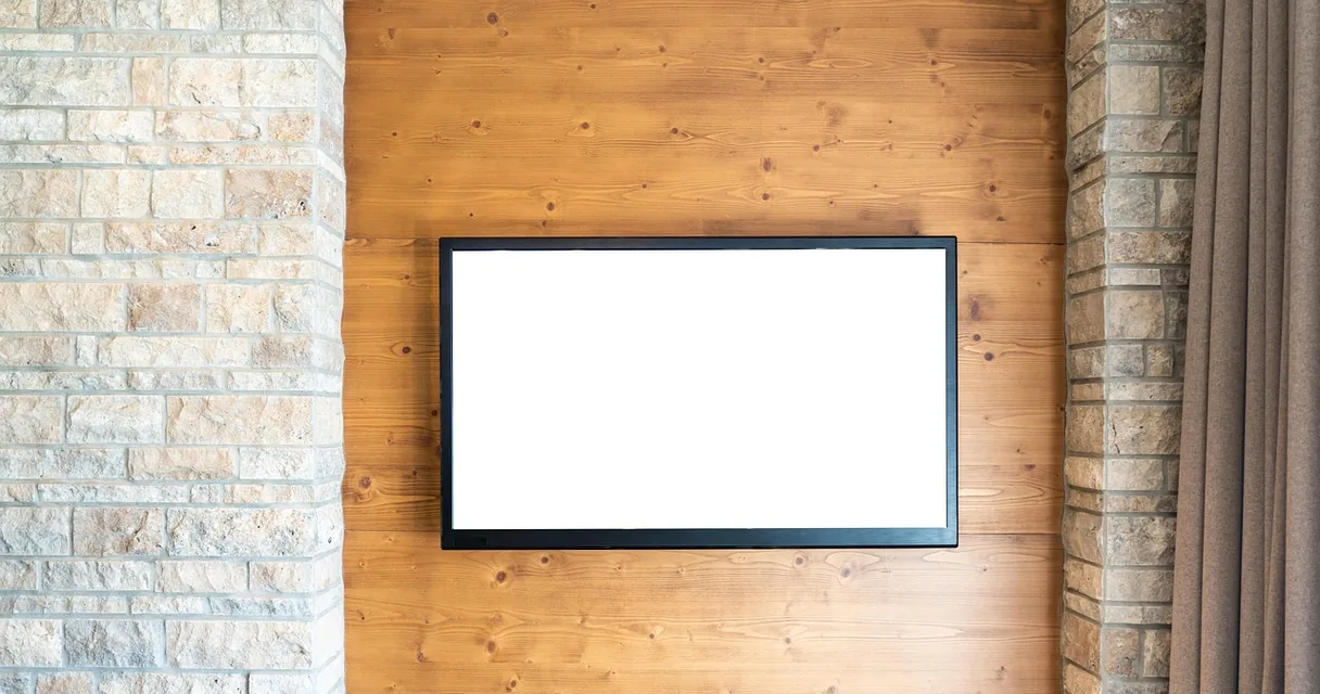 Televisão de tela plana fixada em parede de madeira e tijolos, ilustrando o IPTV em TV de 32 polegadas